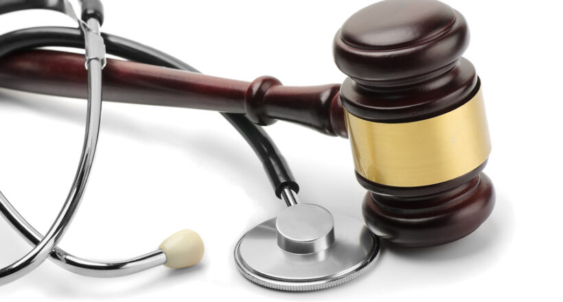 Close up of stethoscope and gavel on white background
